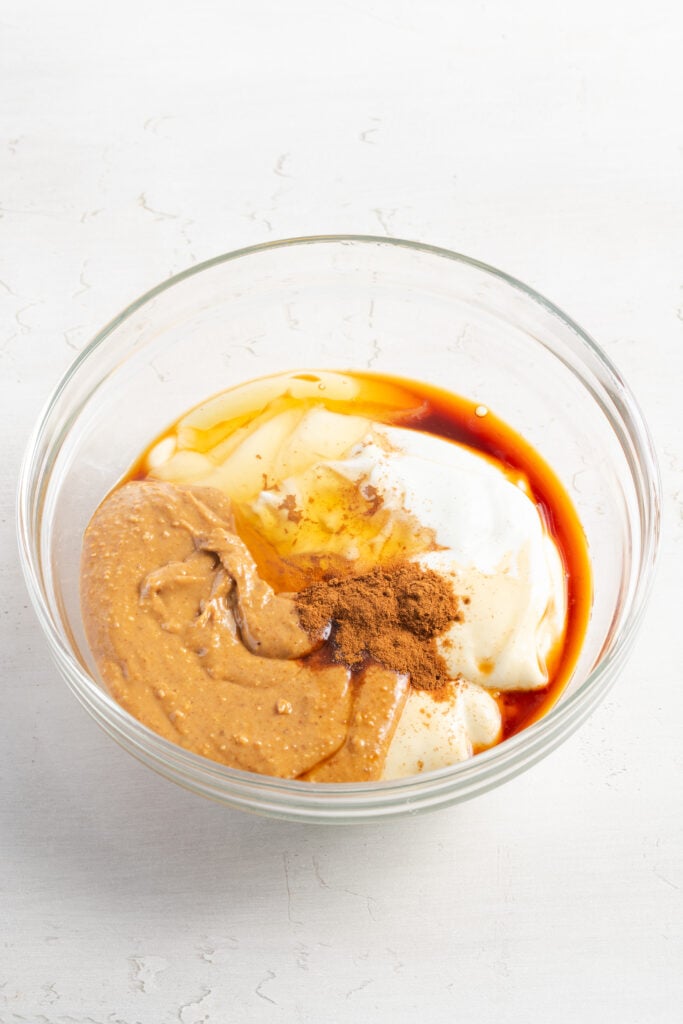 Greek yogurt, peanut butter, honey, vanilla, cinnamon added to a mixing bowl.