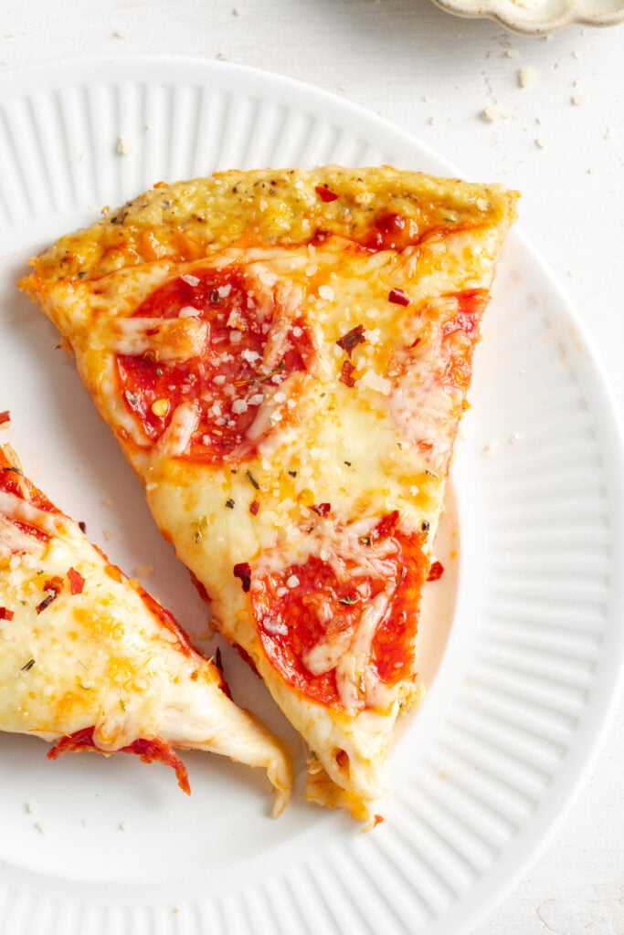 closeup shot of pepperoni chicken crust pizza on a white plate.