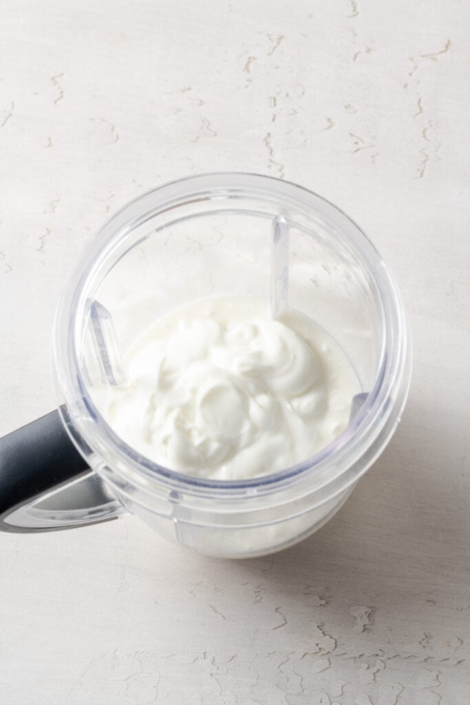 cottage cheese and greek yogurt added to a blender pitcher.