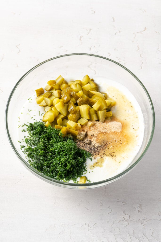 ingredients for making dill pickle dip added to a mixing bowl.