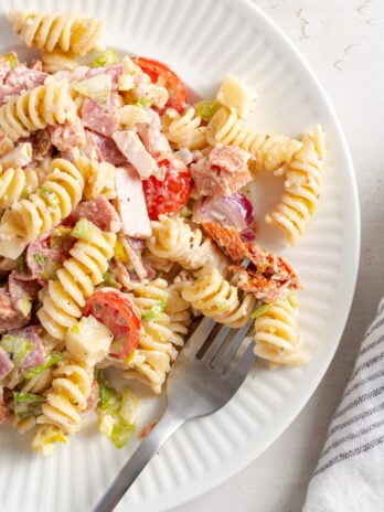 silver forkful of grinder pasta salad showing the mix of fresh veggies, tender pasta, three kinds of meat, and cheese chunks.