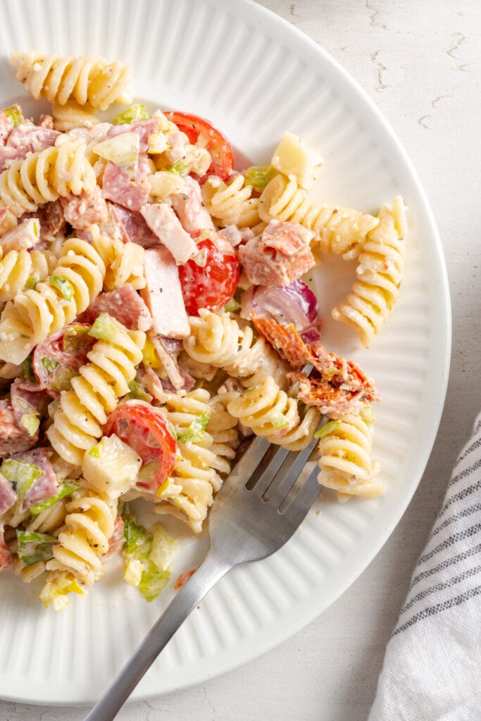 silver forkful of grinder pasta salad showing the mix of fresh veggies, tender pasta, three kinds of meat, and cheese chunks.