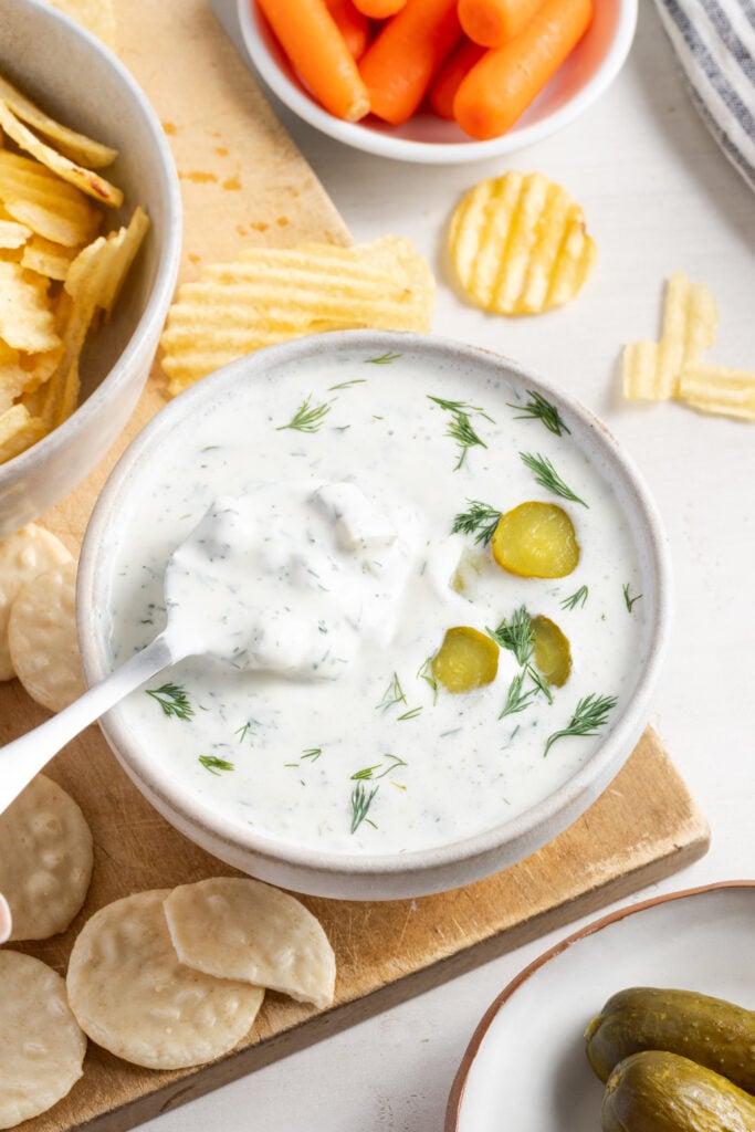 silver spoon taking a bite of easy high protein dill pickle dip from a white bowl.