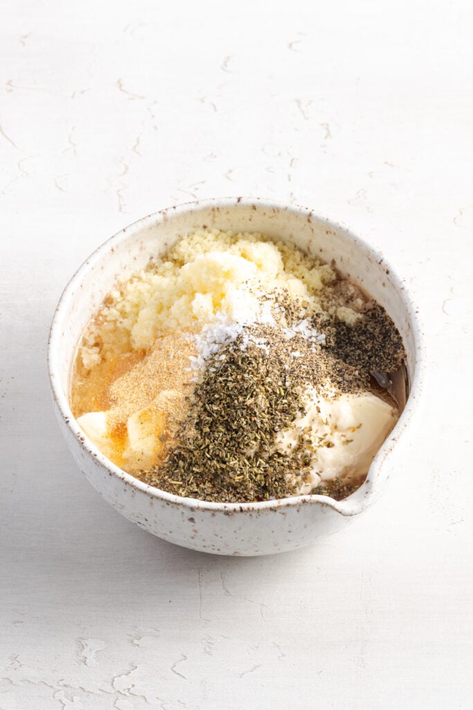 ingredients for grinder salad dressing added to a small mixing bowl.