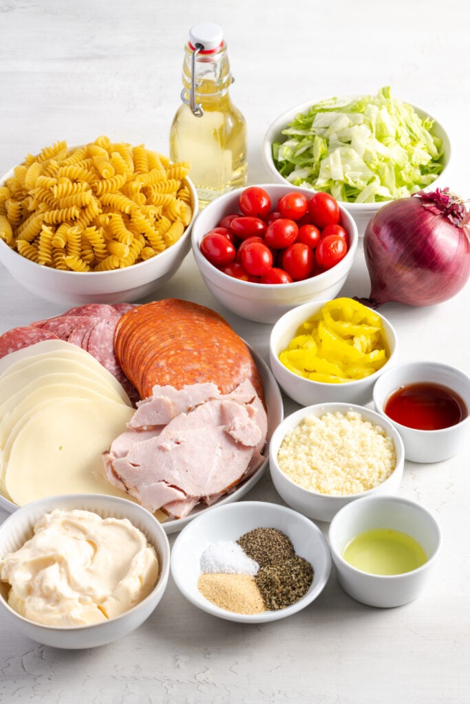 ingredients needed to make italian grinder pasta salad recipe measured out on a white table.