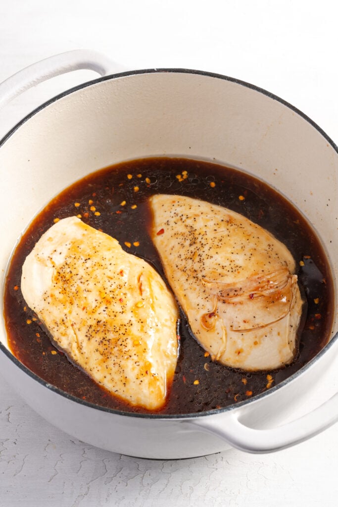 seared chicken breasts nestled into the dutch oven with the sesame sauce for braising.