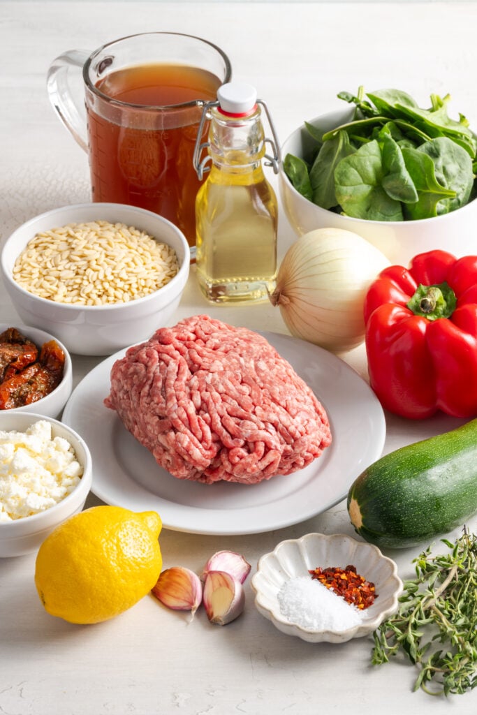 ingredients needed for making greek ground beef orzo skillet recipe measured out on a white table.