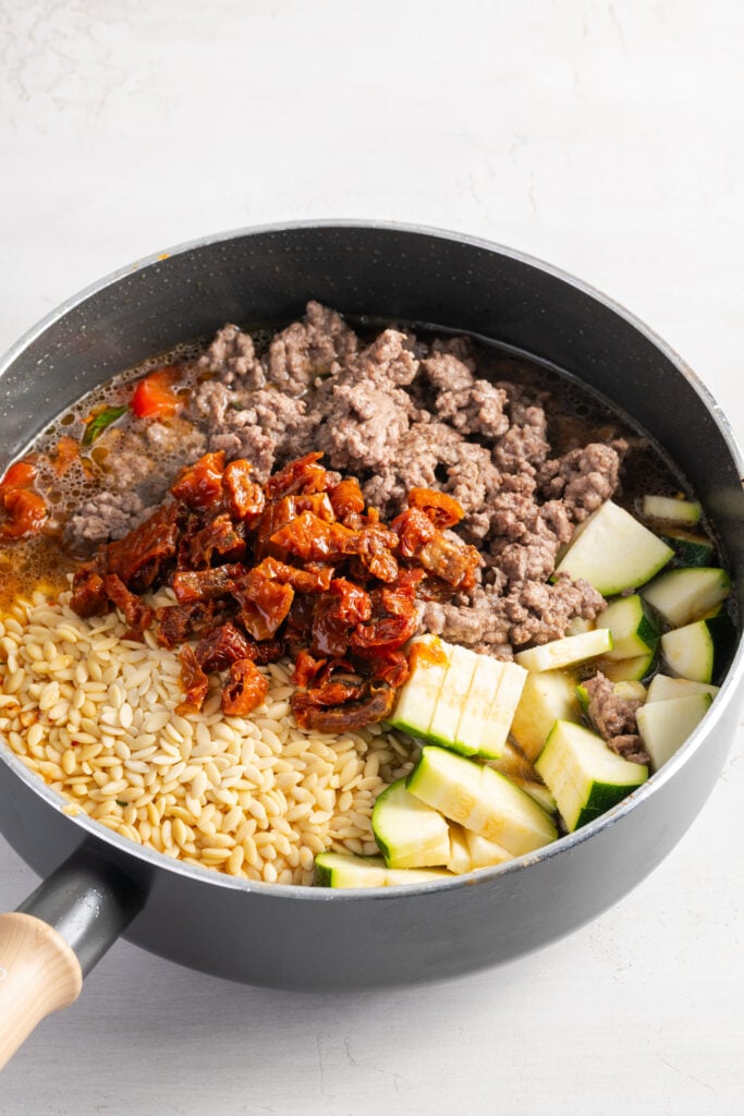 ground beef, zucchini, and tomatoes added to the skillet with the orzo and broth.