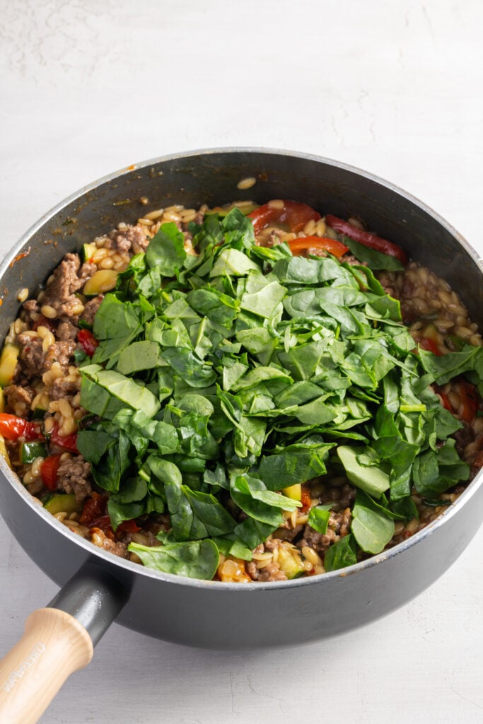 spinach added to the ground beef orzo skillet for wilting.
